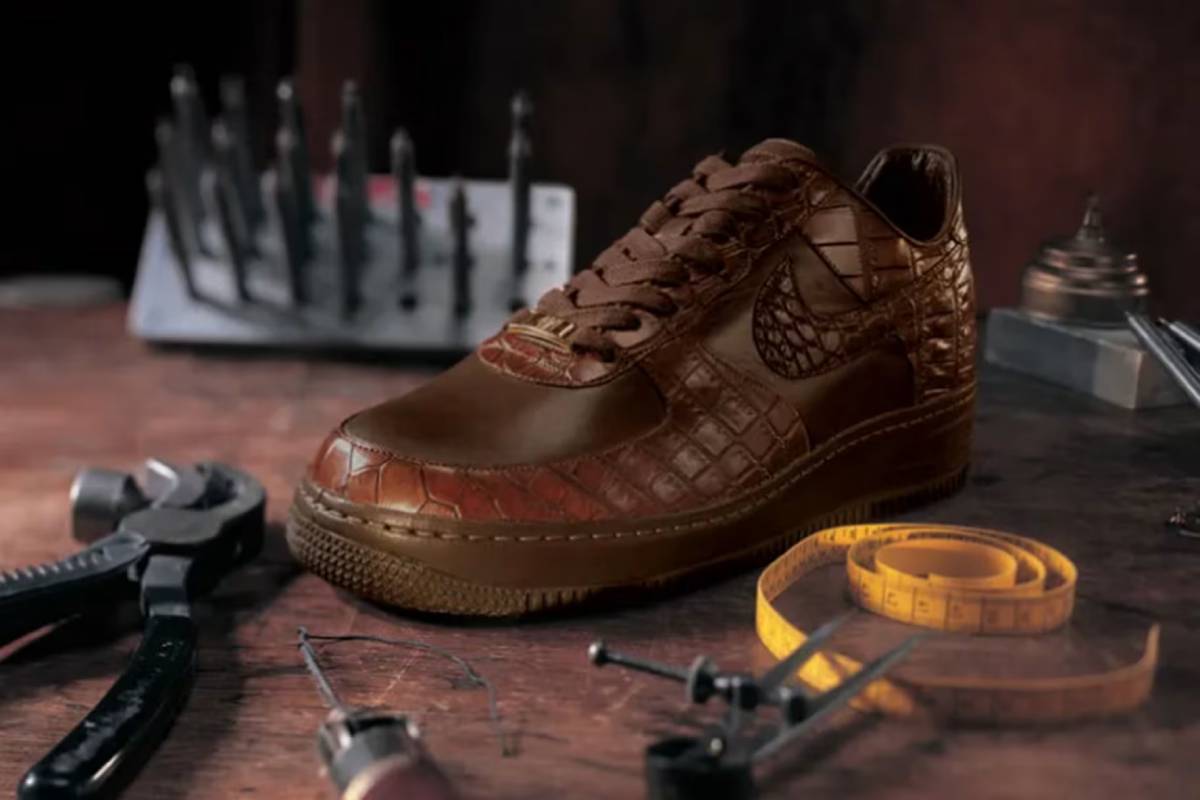 Кафява маратонка Nike Air Force 1 с крокодилска текстура на кожата, поставена в обущарска работилница с инструменти.