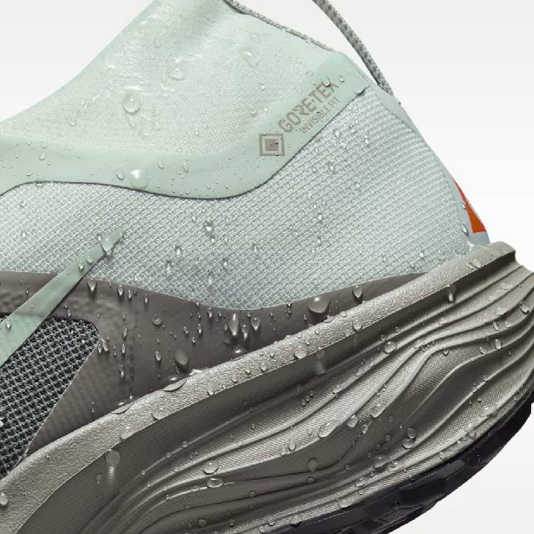 Детайлен изглед на петата на мъжки маратонки Nike Pegasus Trail Gore-Tex в сиво с оранжеви елементи с водна защита и лого Gore-Tex Invisible Fit 