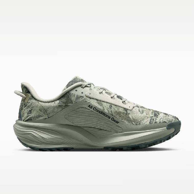 Детайлен изглМъжки обувки за трейл бягане Nike ACG Pegasus Trail с камуфлажен принт в сиво-зелени тонове, надпис All Conditions Gear и дебела омекотяваща подметка ед на дишащата мрежеста материя с графичен принт, текстилните връзки и надписа Wildhorse 10 върху езика на мъжки обувки за трейл бягане Nike   