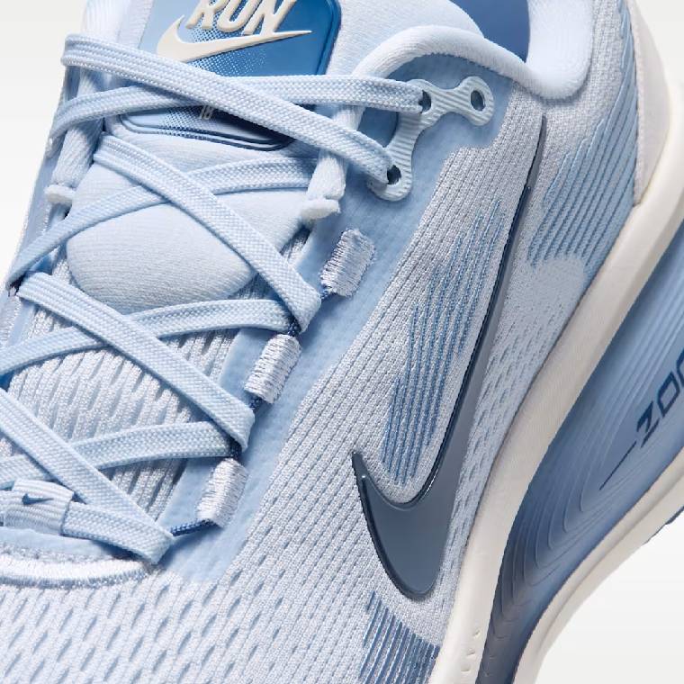 Близък план на горната част на светлосини дамски маратонки Nike Vomero 18 с тъмносиньо лого и сини връзки 